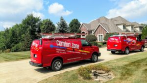 Two Comfort Zone Service trucks parked outside of a large brick home