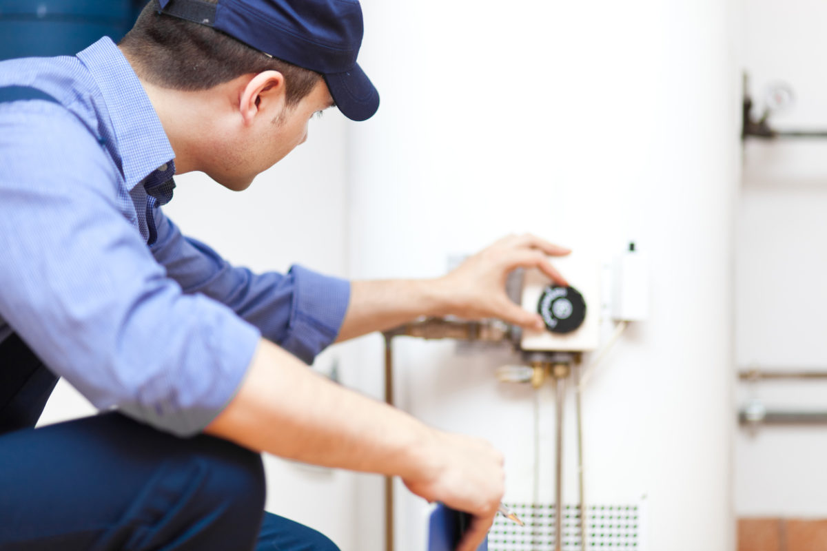Technician adjusting temperature on a white tank water heater